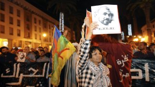 epa06011034 Protesters hold a placard depicting Nasser Zafzafi, leader of the protest movement in the Rif region, and an Amazigh Flag during a demonstration in solidarity with the Rif region and against corruption, repression and unemployment in Rabat, Morocco, 05 June 2017. EPA/ABDELHAK SENNA